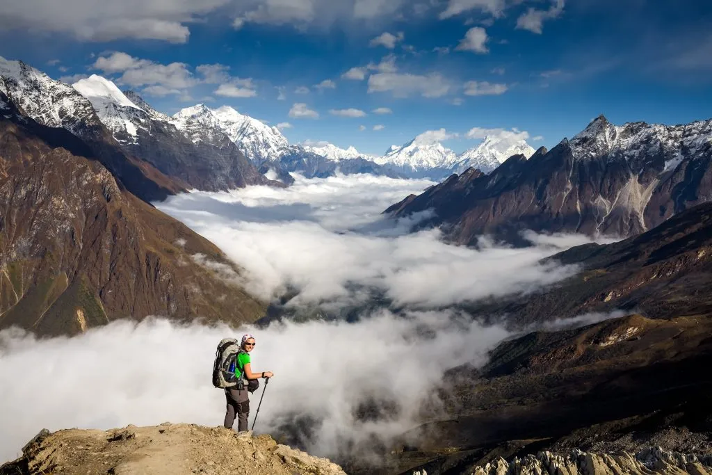 Trekker op weg naar de met wolken bedekte vallei tijdens de Manaslu trektocht in Nepal